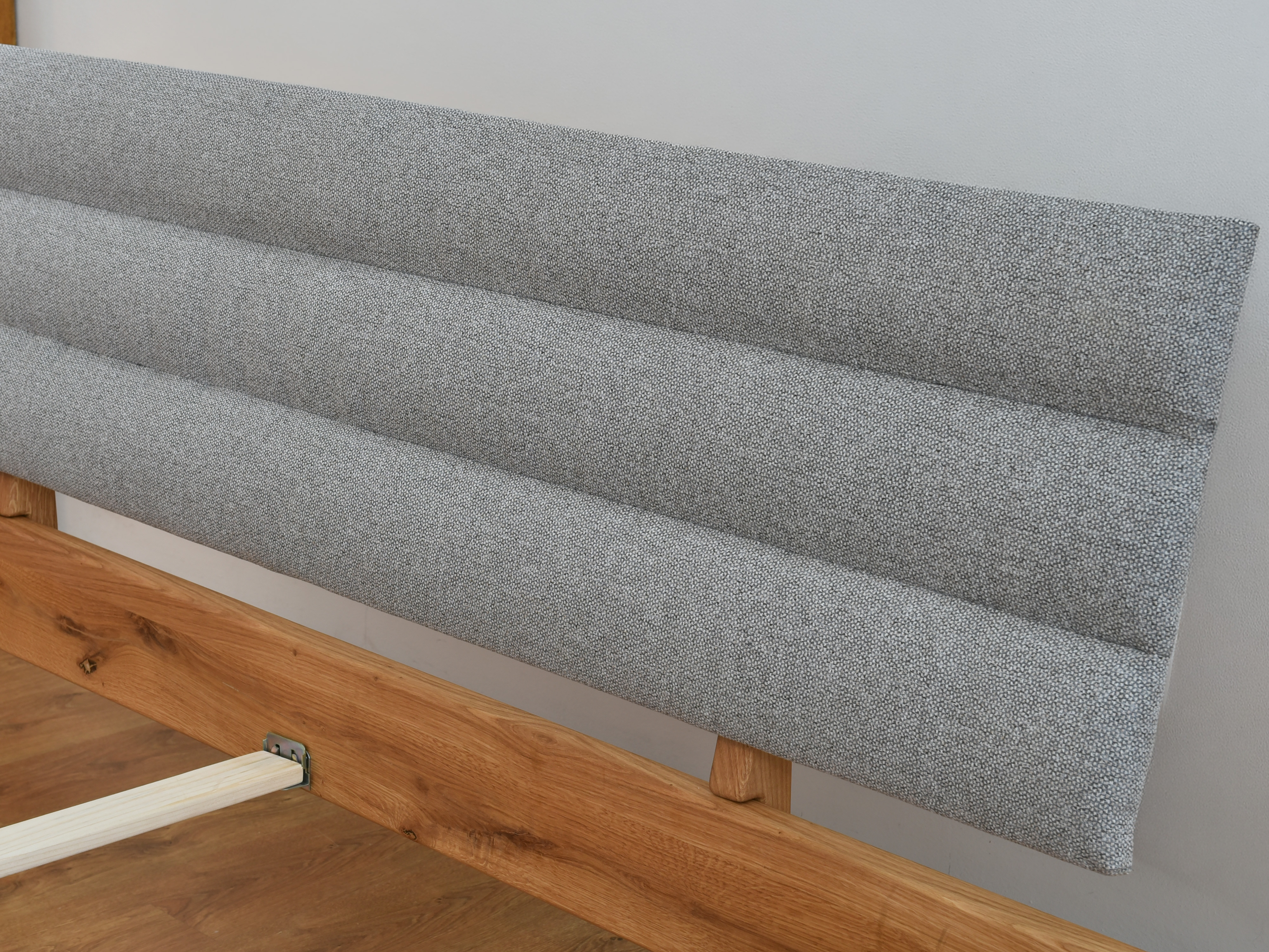 Detail čalúneného sivého čela dubovej postele Matej